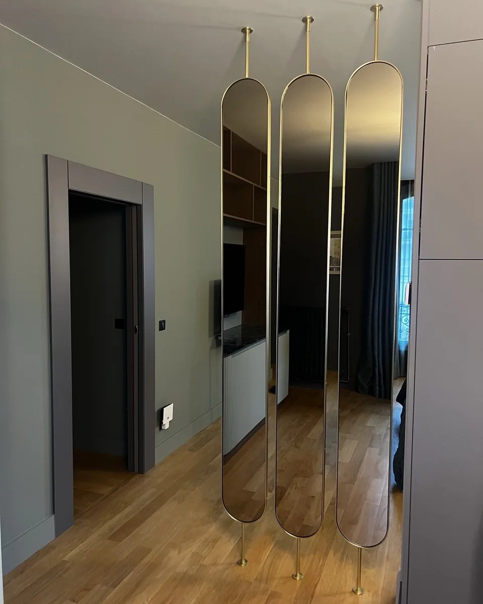 Trois hauts miroirs ovales cerclés de laiton, montés sur pivot entre sol et plafond