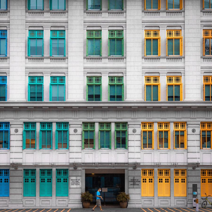 Façade blanche aux fenêtres encadrées de vert et de jaune